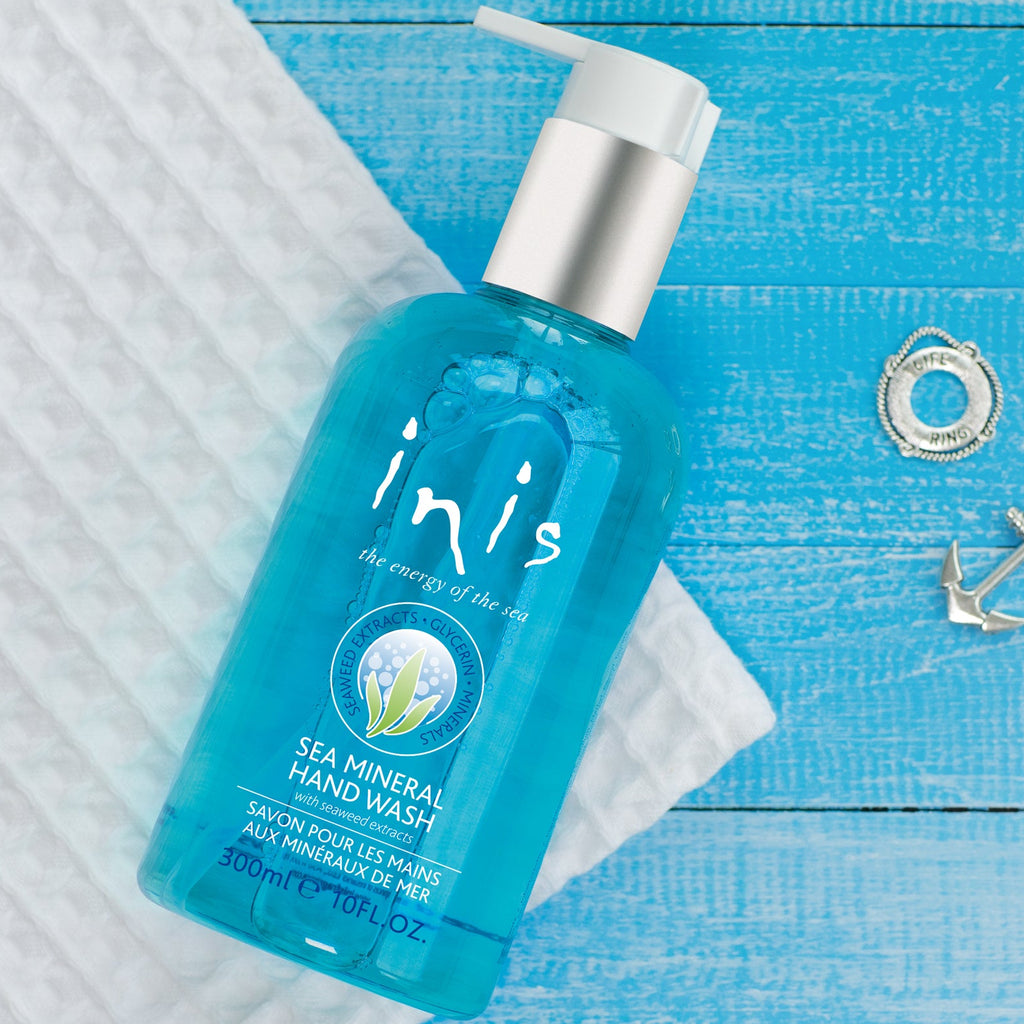 Blue bottle of 'inis' sea mineral hand wash on a blue wooden surface with decorative elements.