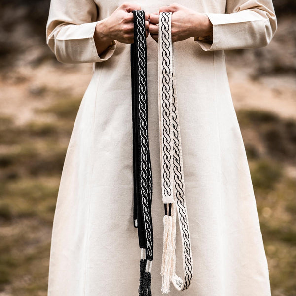 Person holding two braided leather straps against a natural background