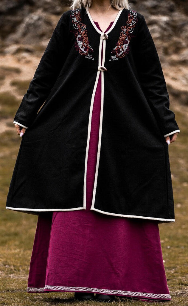 Person wearing a black and purple dress with embroidery in an outdoor setting