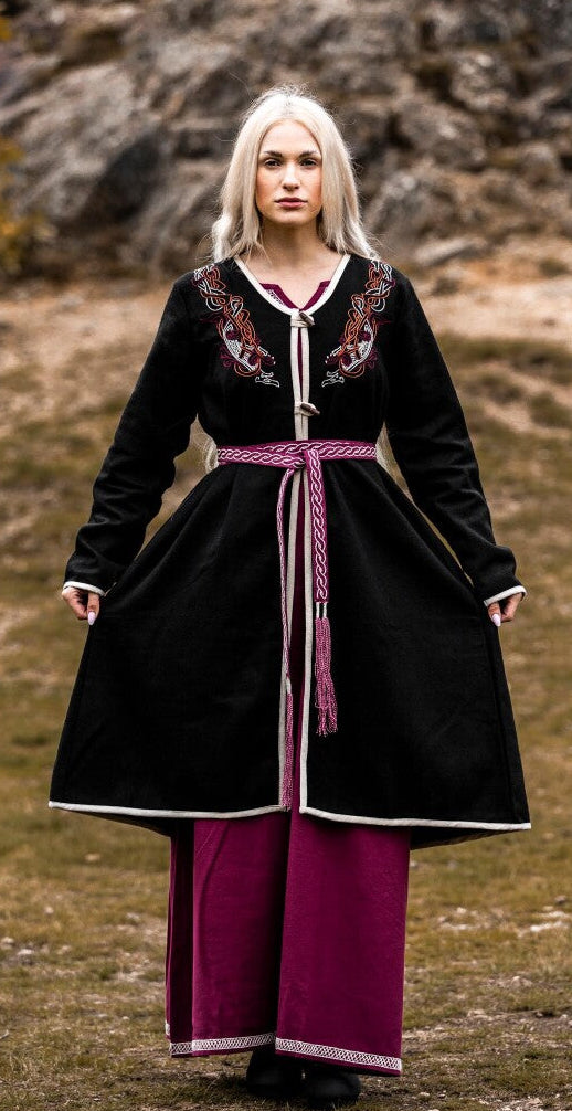 Person wearing a black and purple dress standing in a rocky outdoor setting
