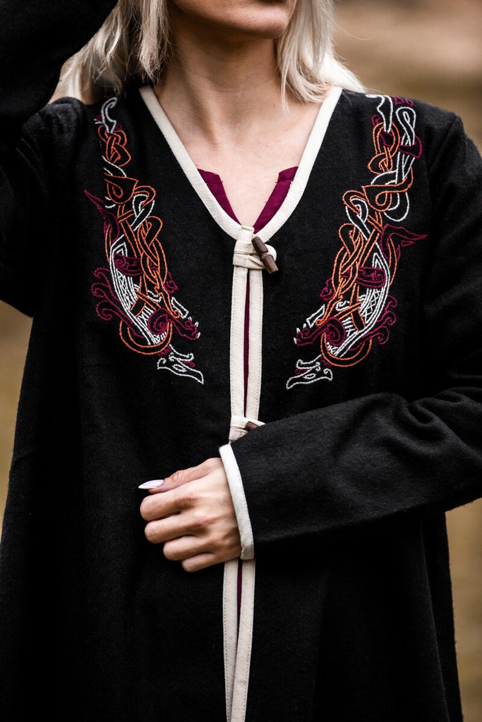 Black embroidered dress with white trim worn by a person, blurred background