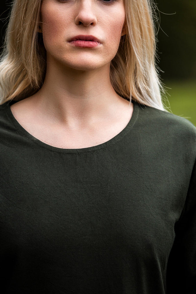 Woman wearing a dark green dress with a blurred background
