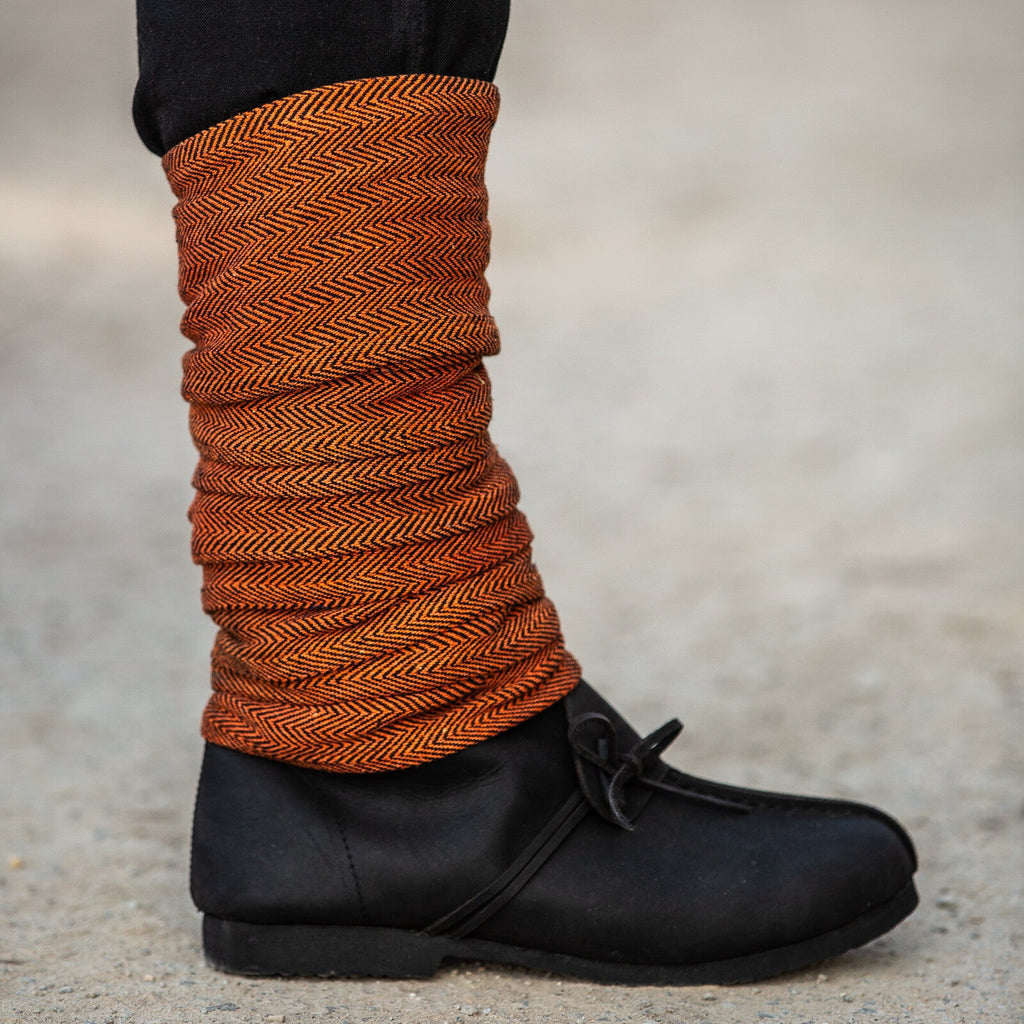 Person wearing black shoes with orange leg warmers on a blurred background