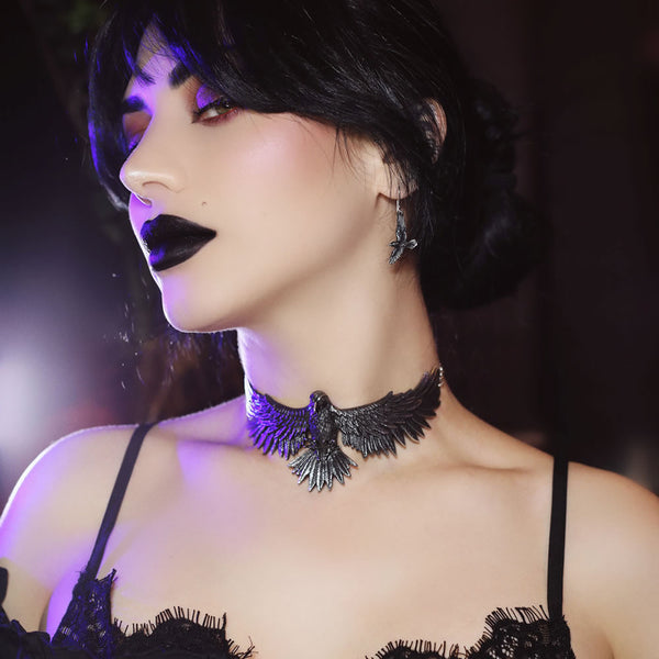 Woman wearing a black lace dress and choker with dark makeup.
