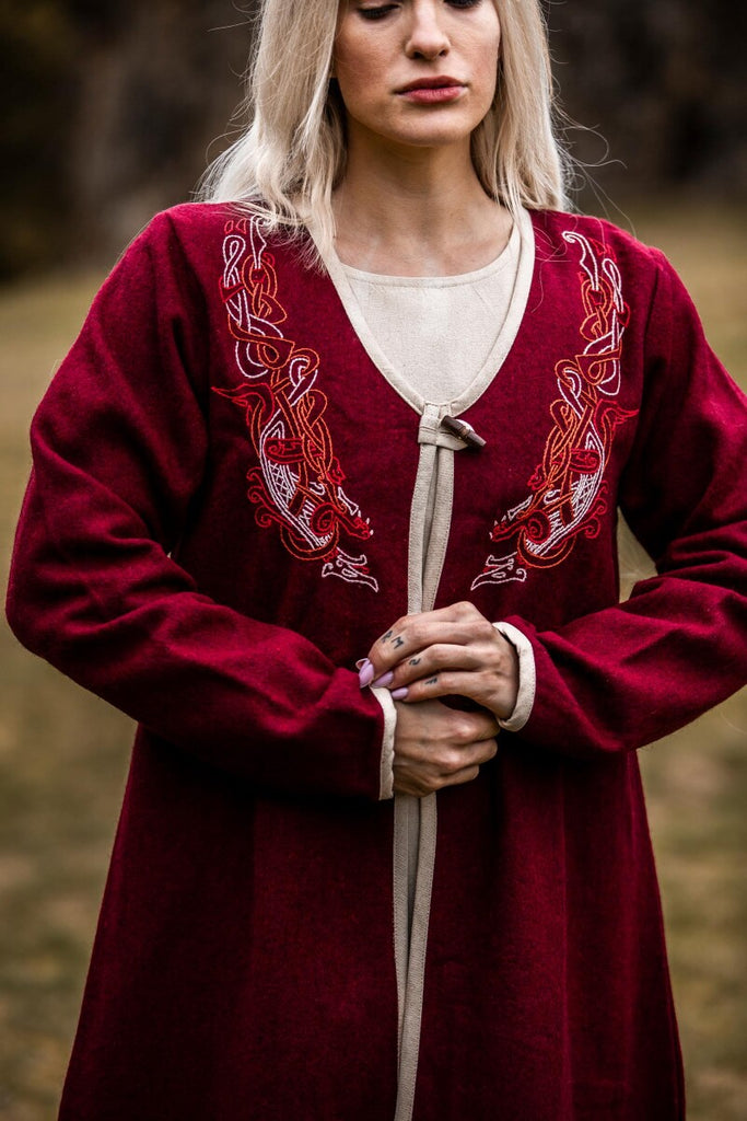 Woman wearing a red embroidered dress with a blurred natural background
