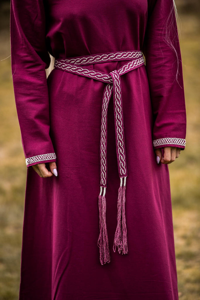 Maroon dress with a braided belt against a blurred natural background